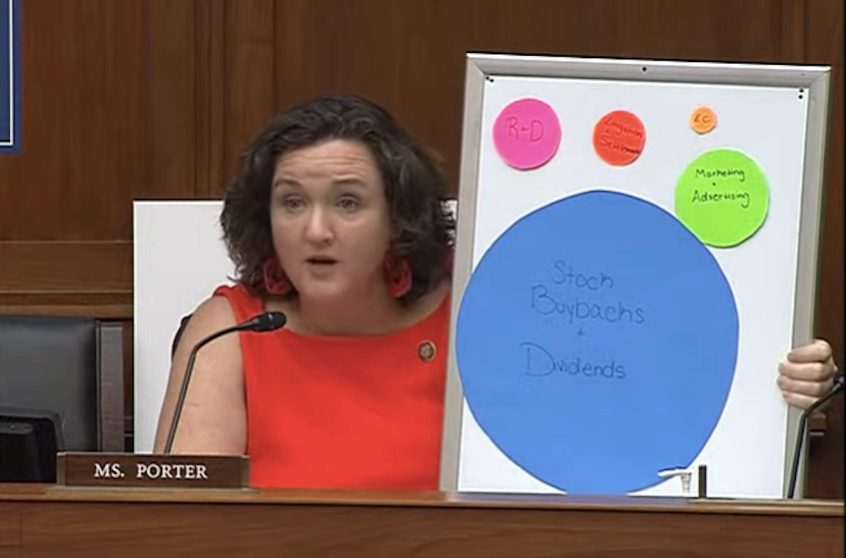 Katie Porter holds a whiteboard with cardboard paper circles of various sizes stuck to it during a hearing.