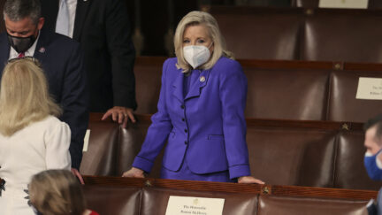 Liz Cheney stands by herself as people talk around her in the House chamber before Biden's address.