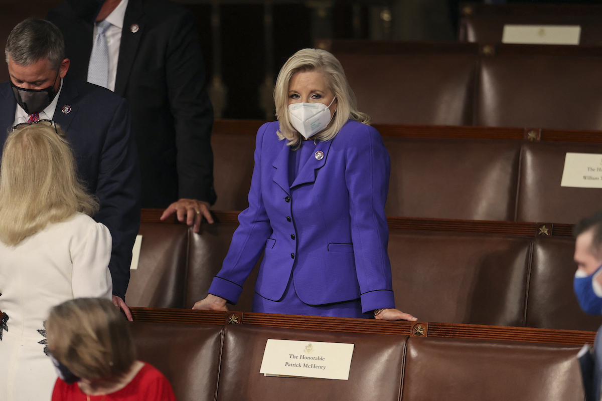 Liz Cheney stands by herself as people talk around her in the House chamber before Biden's address.