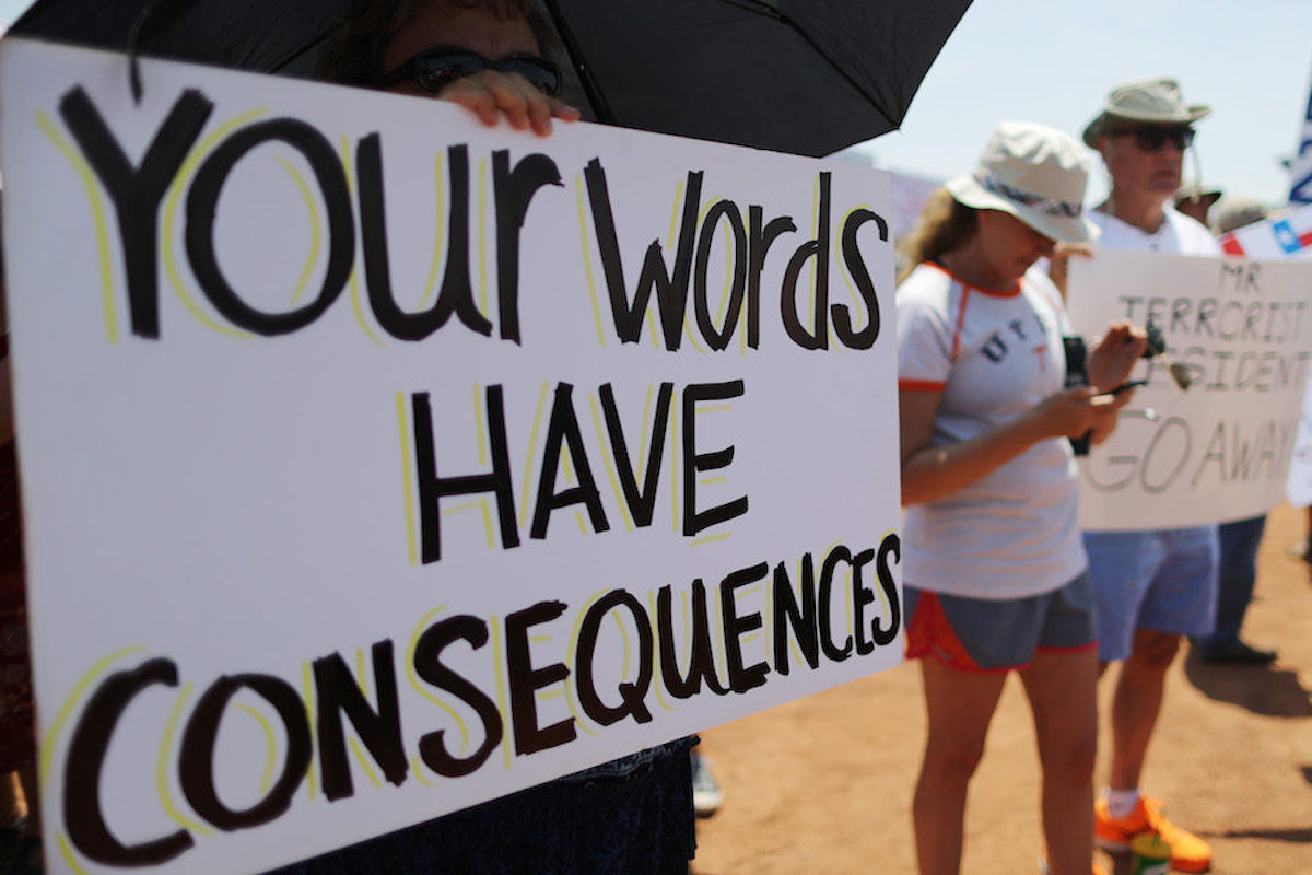 A protester holds a sign reading "Your words have consequences"