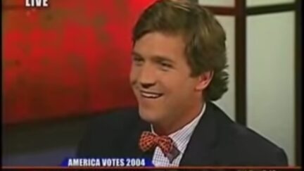 Tucker Carlson smirks in an old CNN clip above a chyron reading 