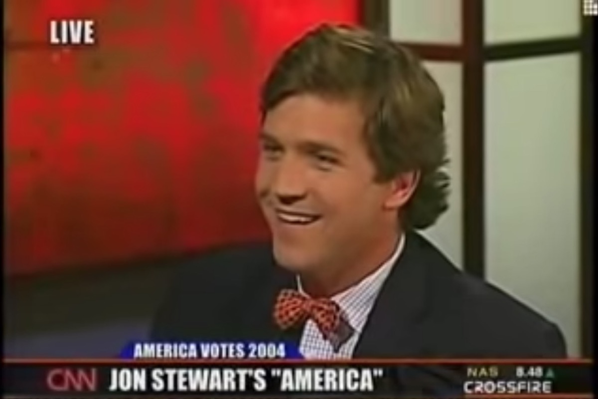 Tucker Carlson smirks in an old CNN clip above a chyron reading "Jon Stewart's 'America'"