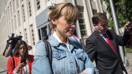 Allison Mack exits court with her arms folded, looking down, wearing a denim jacket.