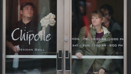 An employee cleans the glass door of a Chipotle location.