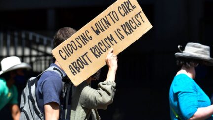A black lives matter supporter marches holding a sing reading 