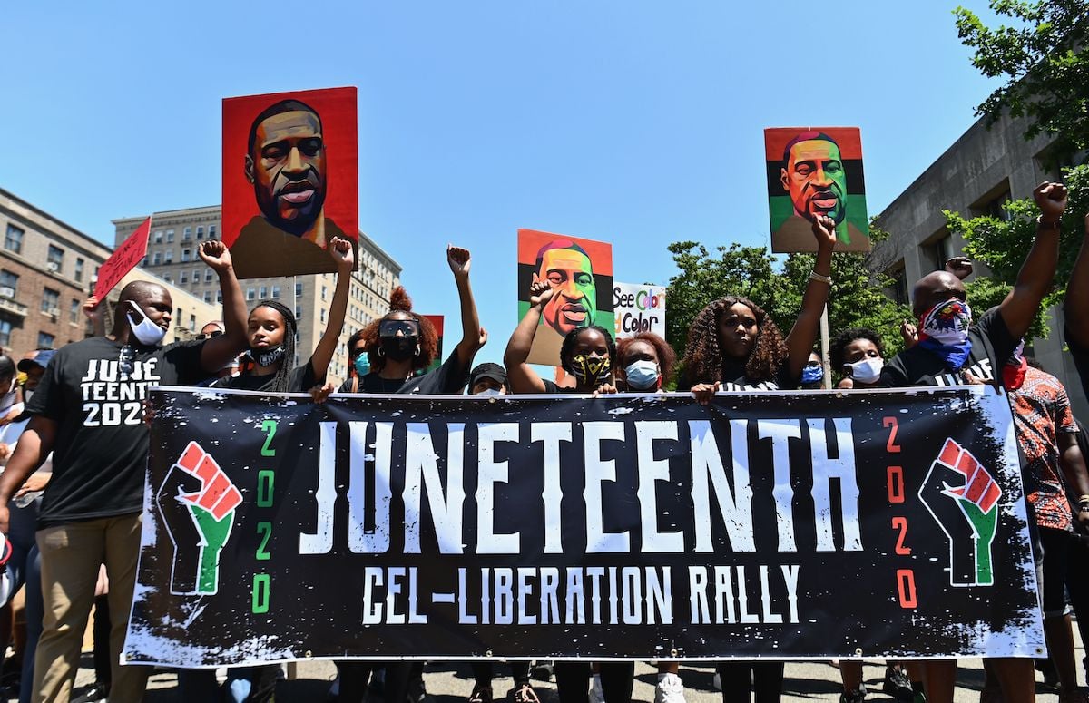 Protestors hold pictures of George Floyd as they march during a Juneteenth rally