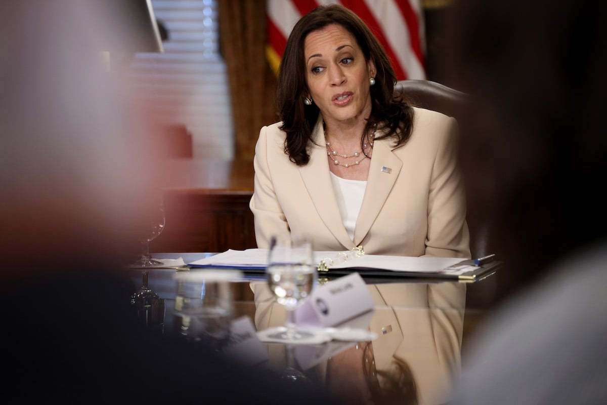 Kamala Harris speaks from a table, viewed through the shoulders of the people sitting across form her.