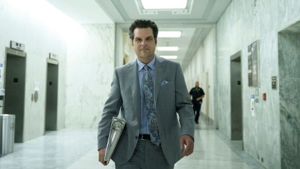 Matt Gaetz walks through a hallway looking slightly disheveled, holding a binder.