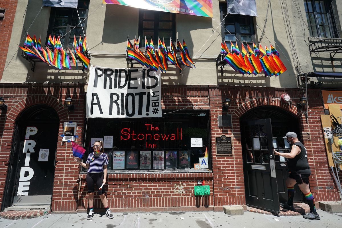 The Stonewall Inn in New York flies LGBTQIA flags and a sign reading "Pride is a riot #BLM"