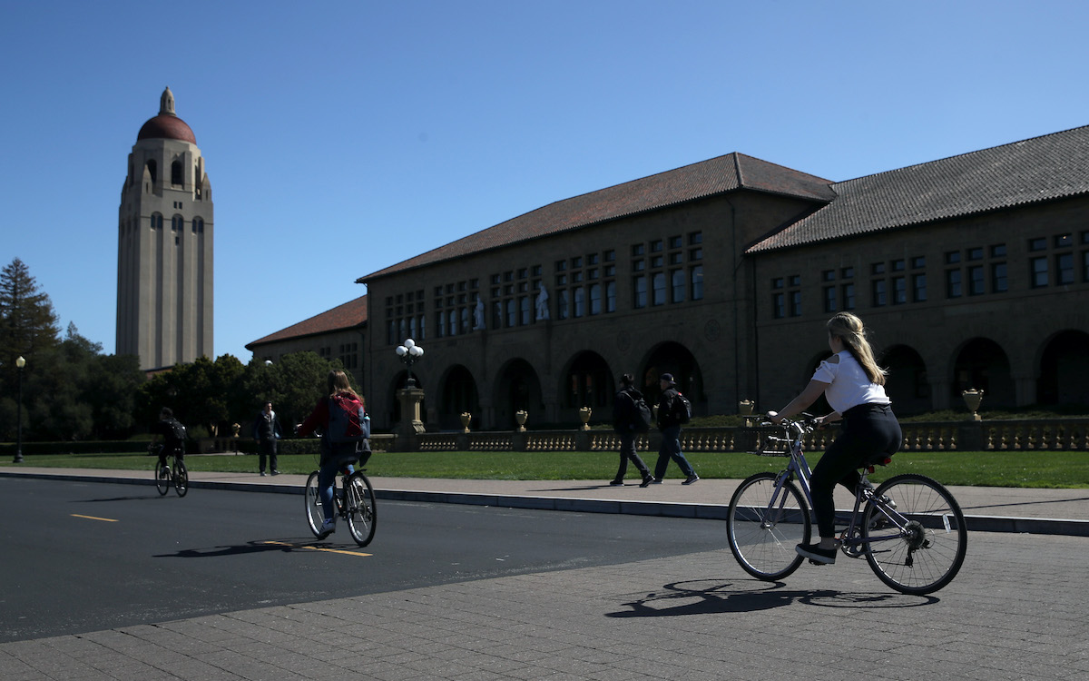 Cyclists ride by Hoover Tower on the Stanford University campus