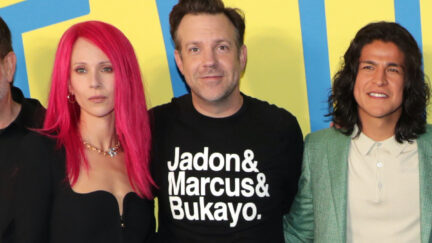 Jason Sudeikis on the carpet for Ted Lasso wearing a sweatshirt reading 