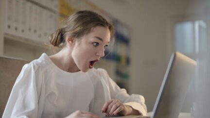 Woman with shocked looked on her face as she reads email on laptop.