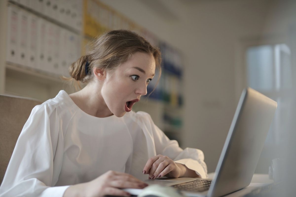 Woman with shocked looked on her face as she reads email on laptop.
