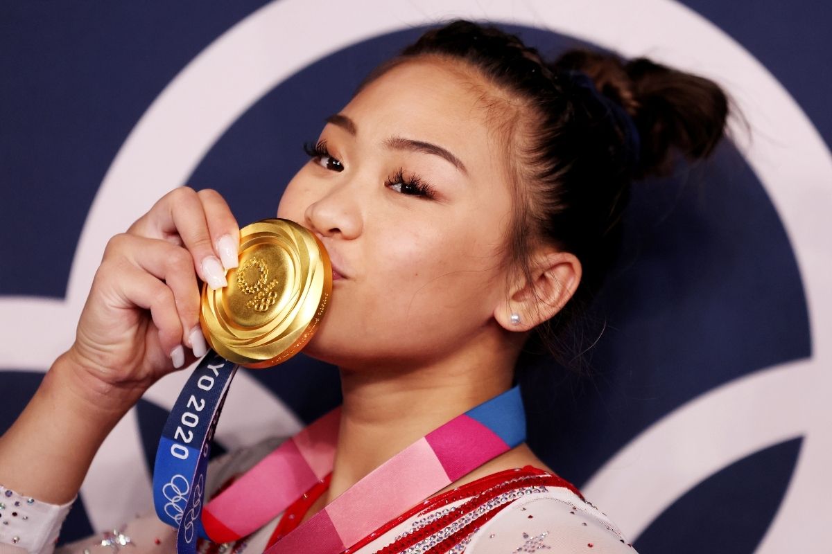Sunisa Lee wins Olympic Gold at Tokyo Olympics and kisses medal.