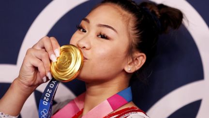 Sunisa Lee wins Olympic Gold at Tokyo Olympics and kisses medal.