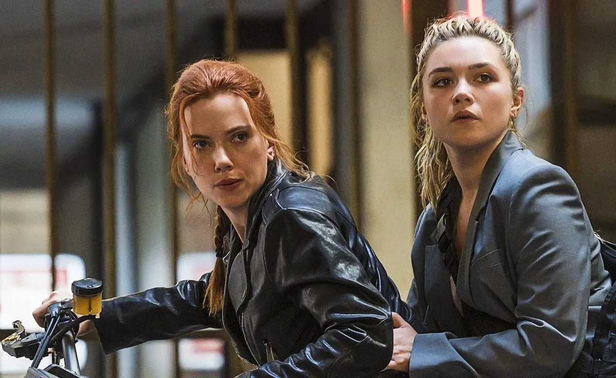 Scarlett Johansson as Natasha Romanoff and Florence Pugh as Yelena Belova sit together on a motorcycle in the movie 'Black Widow'