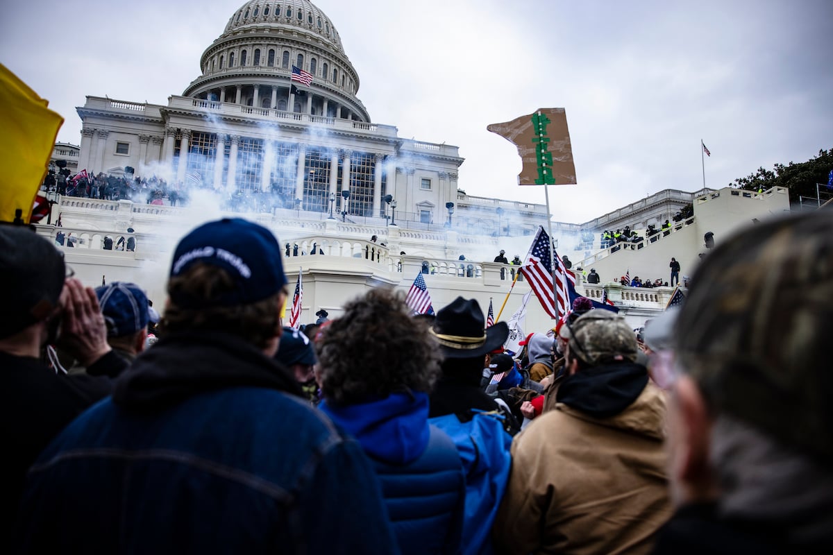 Pro-Trump supporters look on from a crowd in front of the US Capitol building during the Jan 6 insurrection.