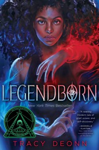 "Legendborn" by Tracy Deonn featuring a Black teenager with voluminous black hair moving red and blue clouds of magic.