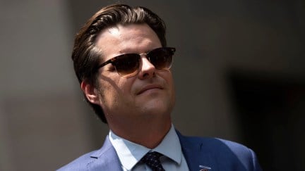 Matt Gaetz wears sunglasses and a suit outside.