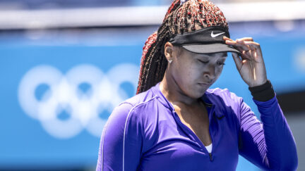 Naomi Osaka adjusts her visor on the tennis court at the Tokyo Olympics