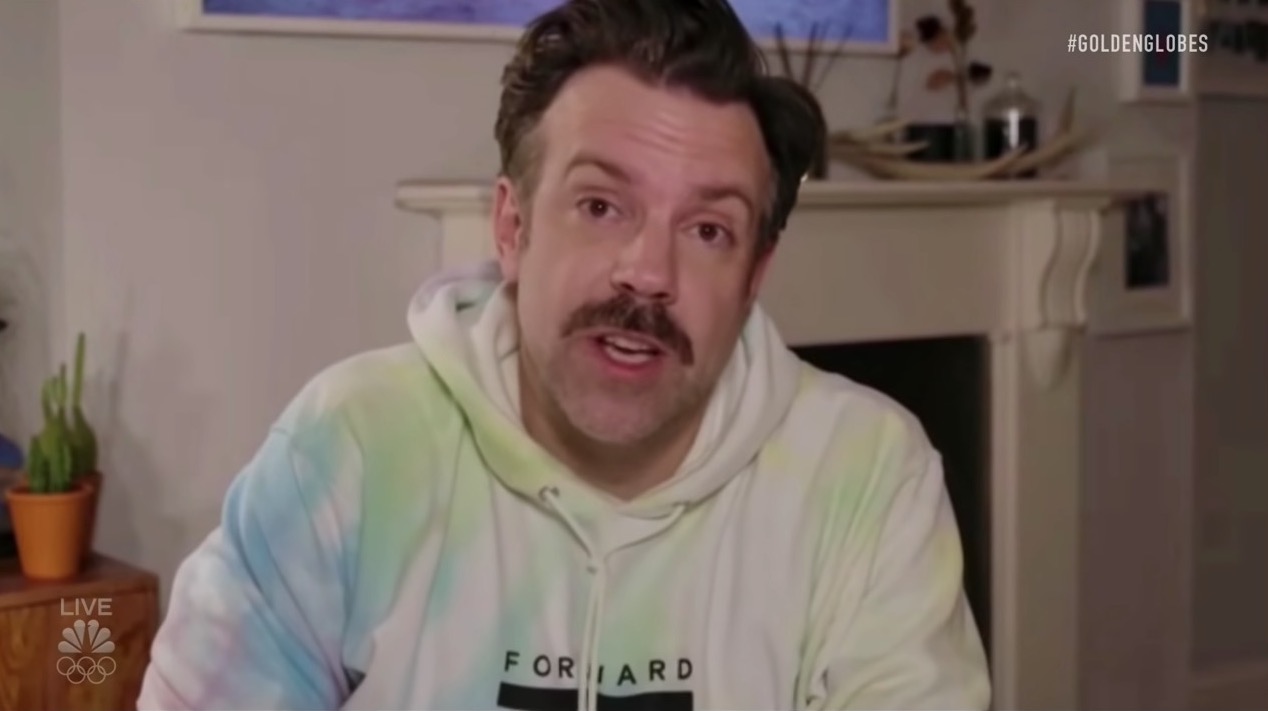 Jason Sudeikis wears a tie-dyed hoodie reading "forward" during a video call.