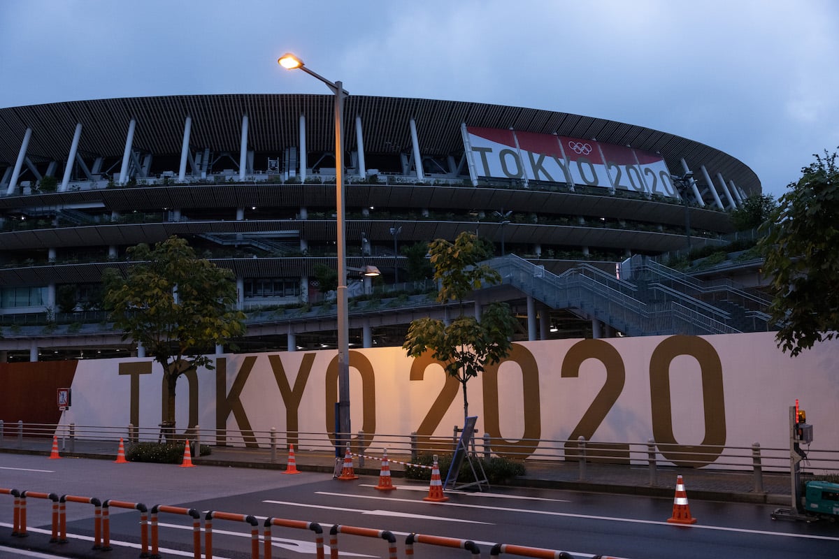 Branding reading TOKYO 2020 is displayed on a fence surrounding the Olympic Stadium