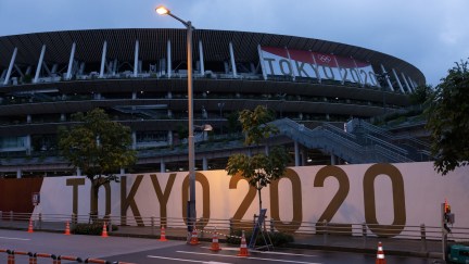 Branding reading TOKYO 2020 is displayed on a fence surrounding the Olympic Stadium