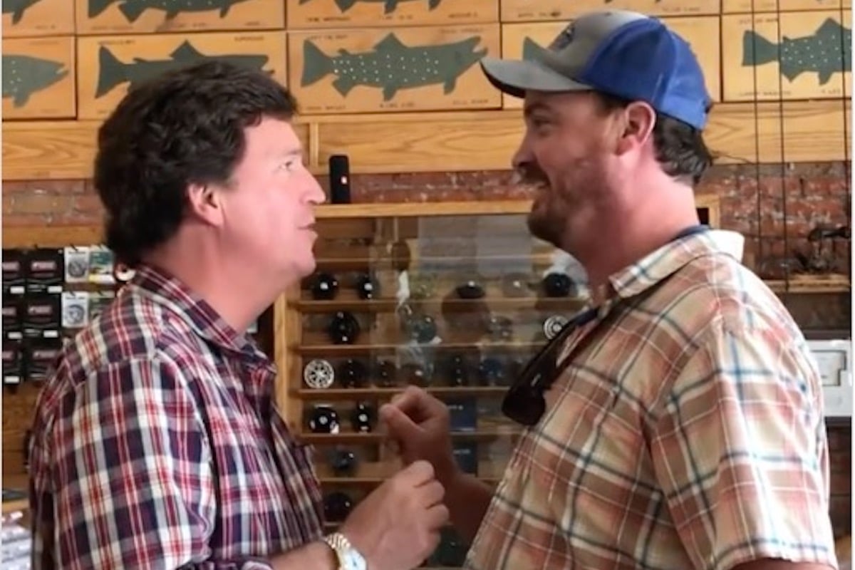 A man confronts Tucker Carlson in a fishing store.