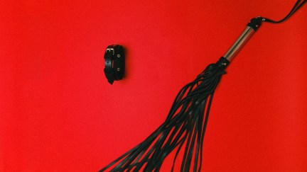 Leather whip on red background.