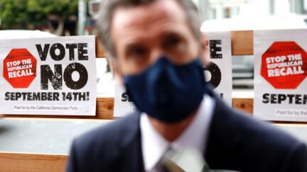 SAN FRANCISCO, CALIFORNIA - AUGUST 13: A sign against the recall is posted behind California Gov. Gavin Newsom as he talks with volunteers who are phone banking against the recall at Manny's on August 13, 2021 in San Francisco, California. California Gov. Gavin Newsom kicked off his 