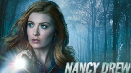 Nancy in the woods with a flashlight in The CW's Nancy Drew banner art.