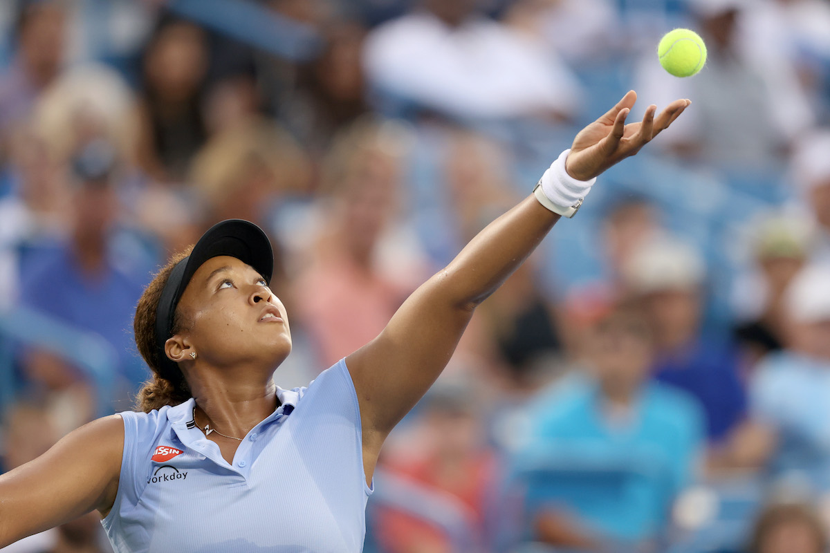 Tennis star Naomi Osaka in mid-serve