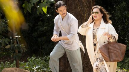 Yao (Manny Jacinto) and Frances (Melissa McCarthy), talking on her cell phone, walk outdoors in a scene from Nine Perfect Strangers.