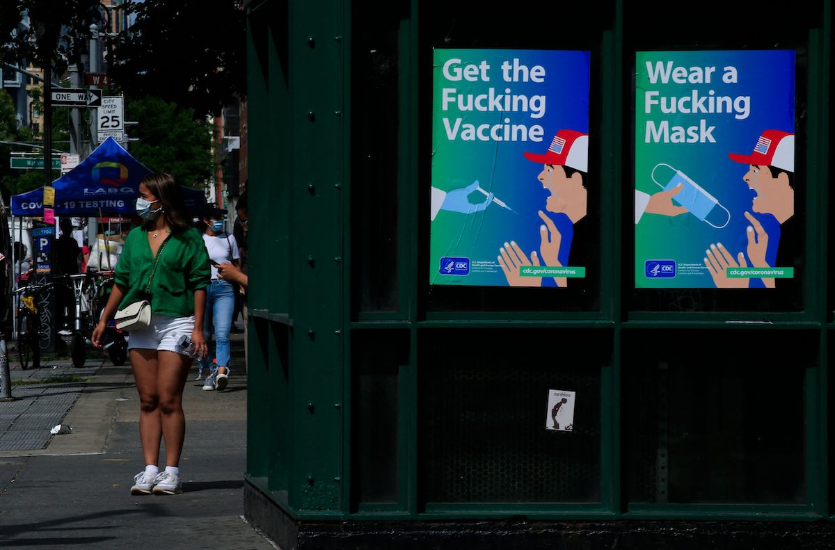 Posters using strong language to warn about Covid-19, bearing the mark of the Department of Health and Human Services (HHS) and the Centers for Disease Control and Prevention (CDC), are on display outside a subway station in New York