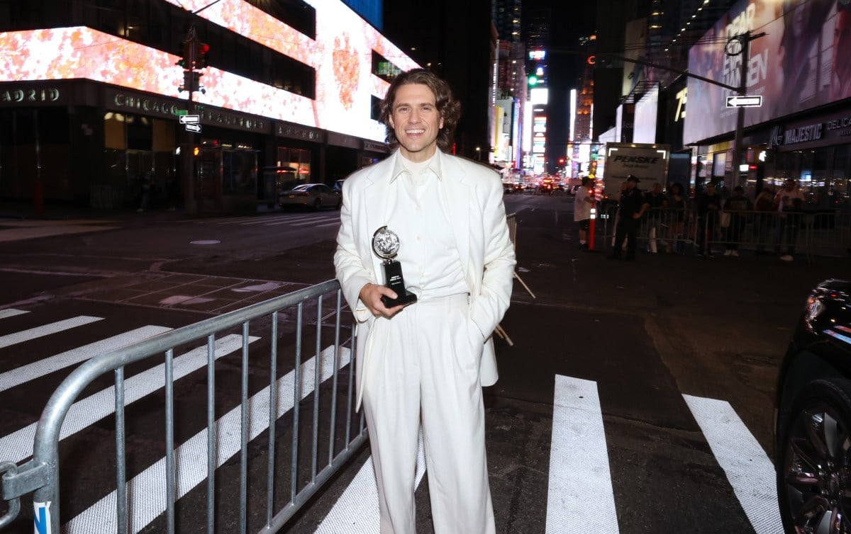 Aaron Tveit holding his Tony award outside on the streets of NYC