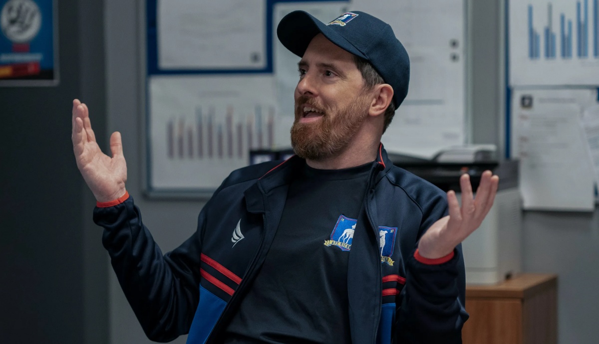 Brendan Hunt as Coach Beard smiling and shrugging.