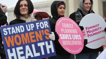 Pro-choice activists hold placards during a rally, one of which reads 