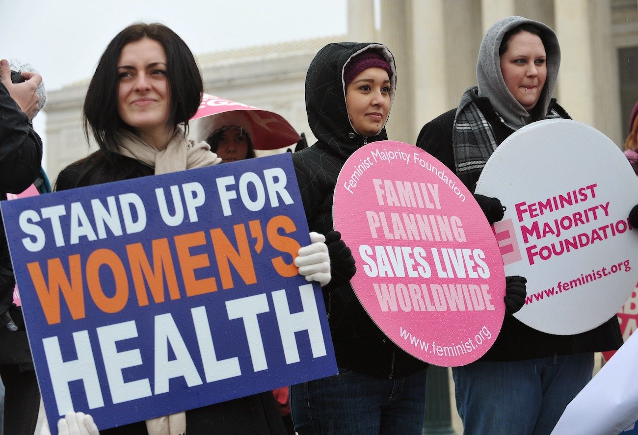 Pro-choice activists hold placards during a rally, one of which reads "Stand up for women's health"