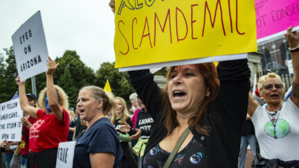 A gathering of anti-vaccine protesters hold signs and yell
