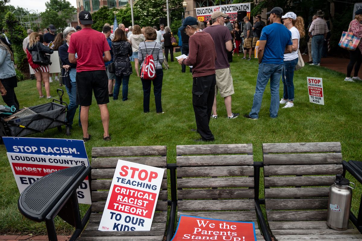 Signs are seen on a bench during a rally against "critical race theory" (CRT) being taught in schools