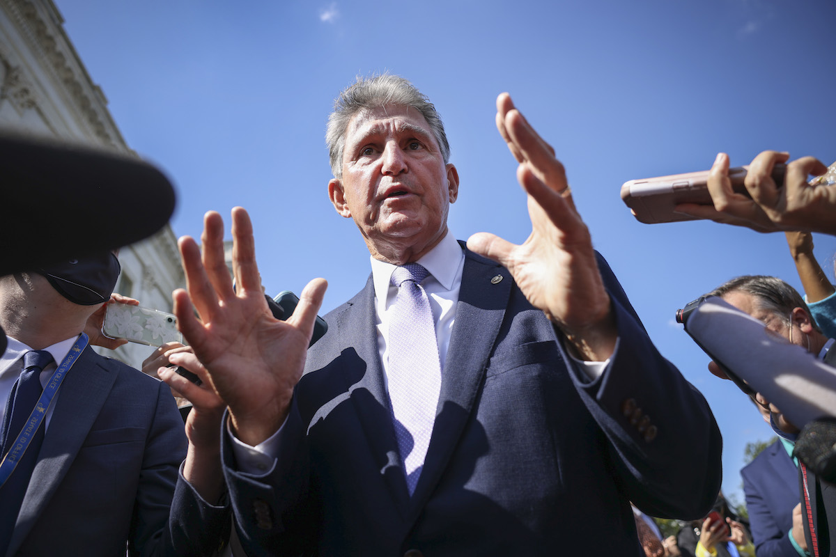 Senator Joe Manchin is surrounded by reporters outside of the Capitol.