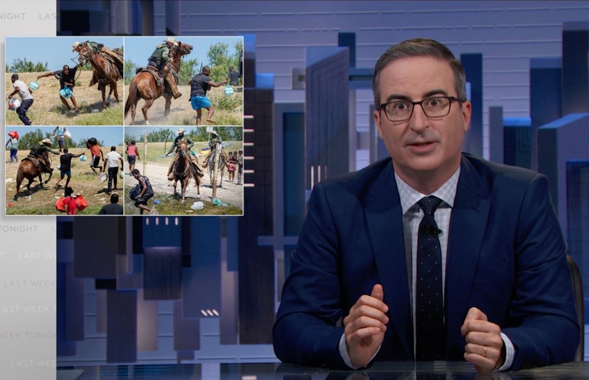 John Oliver sits at his news desk, shows pictures of border patrol assaulting Haitian refugees during a segment on Last Week Tonight