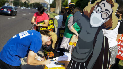 Protesters for green jobs attend a rally featuring a cartoon cutout of Kyrsten Sinema