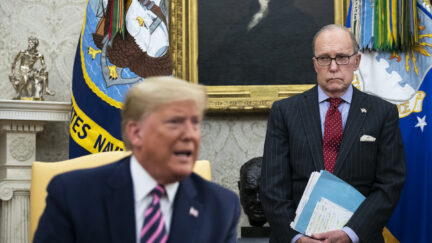 National Economic Council Director Larry Kudlow (R) looks on as then-president Donald Trump speaks to reporters in the Oval Office of the White House