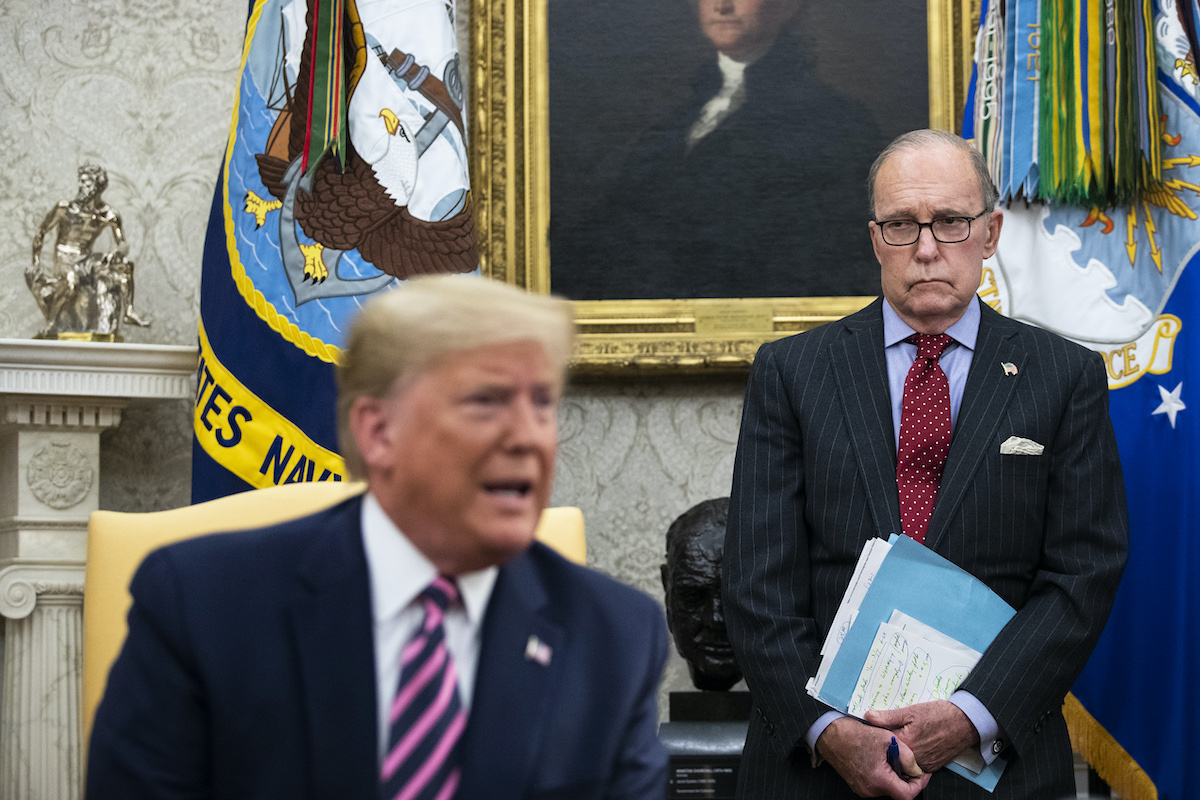 National Economic Council Director Larry Kudlow (R) looks on as then-president Donald Trump speaks to reporters in the Oval Office of the White House