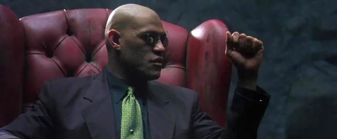 Morpheus (Laurence Fishburne) explaining the history of the war against the Machines to Neo (Keanu Reeves, not pictured) in a chair in the desert in The Matrix.