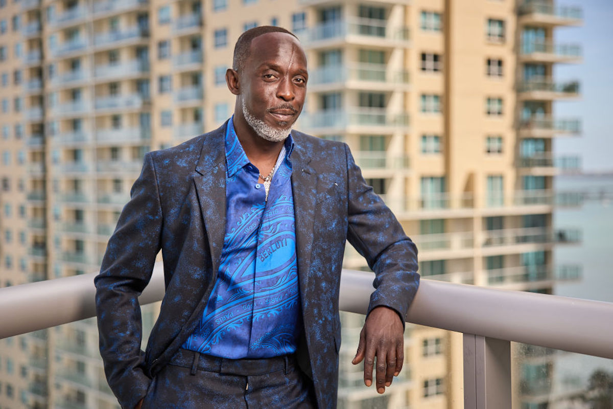 Actor Michael K. Williams in a suit and blue shirt posed on a balcony