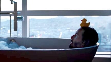 Neo in a bathtub with a rubber duck sitting atop his head in The Matrix Resurrections.