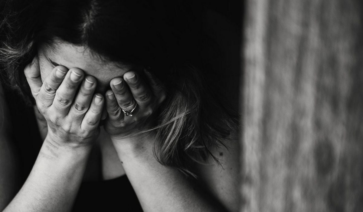 Black and white image of someone crying into their hands. (Image: Kat Jayne on Pexels.)