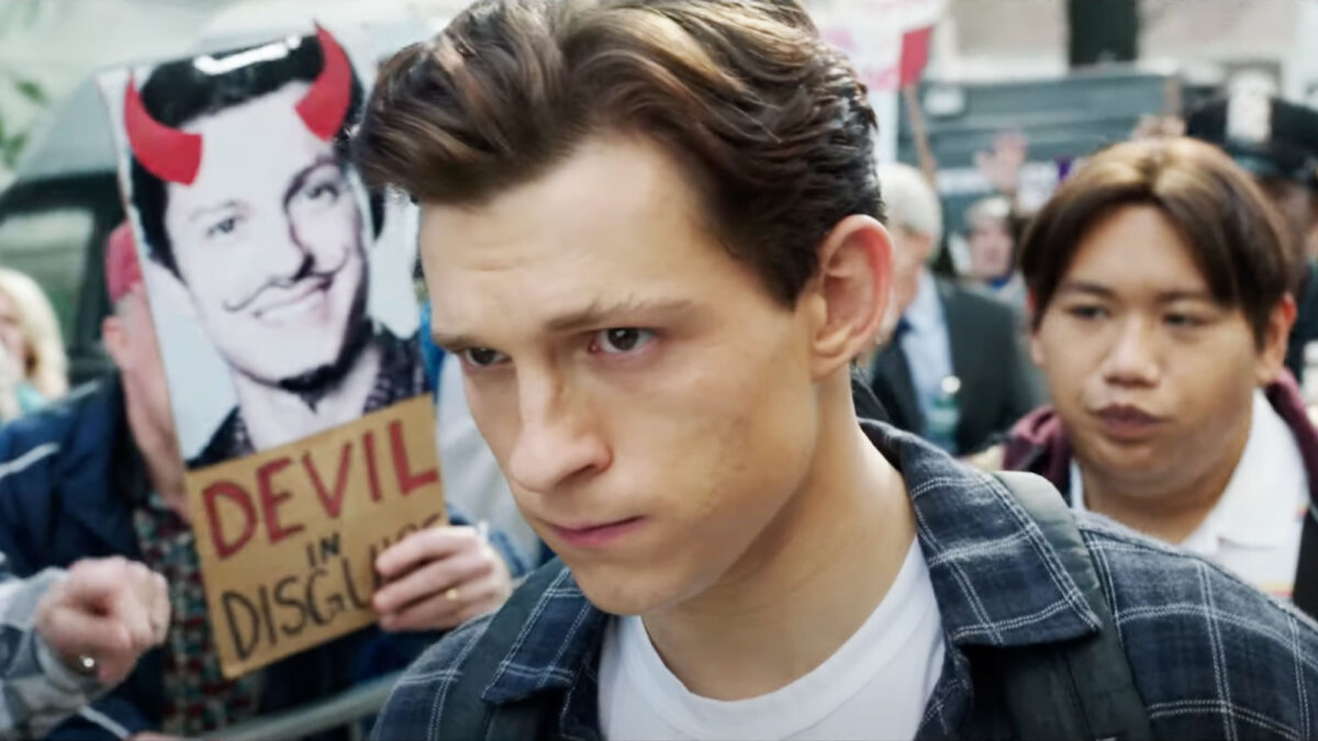 Tom Holland as Peter Parker walking through a protest that says Devil in Disguise